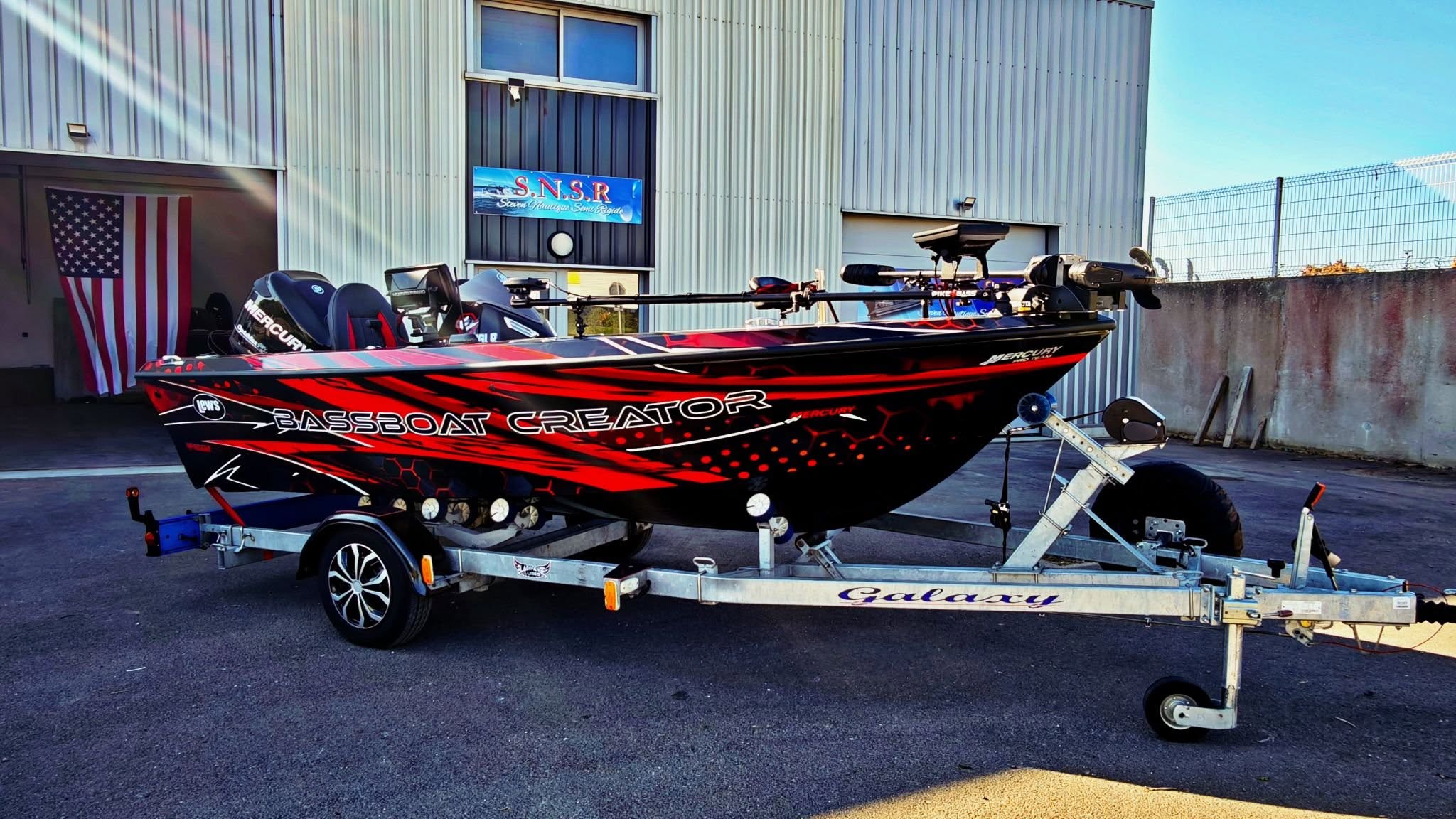 Bass Boat Creator rouge sur remorque devant l'atelier